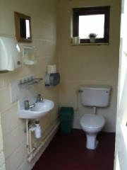 Inside a toilet cubicle, with a washbasin, mirror and window